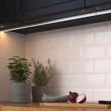 Cuisine moderne avec des lumières led sous les armoires, mettant en valeur les plantes et les oignons sur un comptoir en bois.