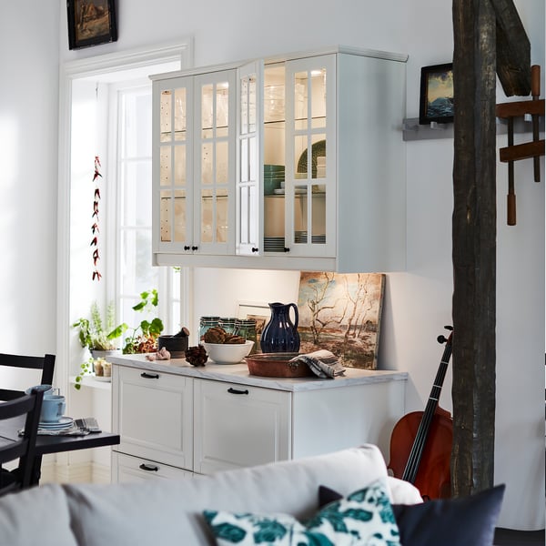 Cuisine blanche avec une armoire en verre, des articles de comptoir et une chaise noire.