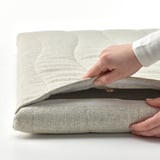 Personne ouvrant un panneau acoustique recouvert de tissu, révélant le noyau en bois, montrant le revêtement amovible.