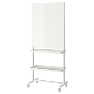 Un tableau blanc mobile MITTZON avec rangement. Il est blanc, rectangulaire, avec des roues pour la portabilité. Il s’agit d’un tableau blanc et d’étagères pour les fournitures.