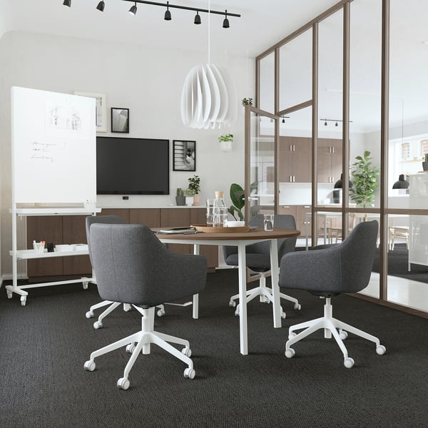 Bureau moderne avec tableaux blancs mobiles MITZZON, chaises grises, télévision et cloison en verre.