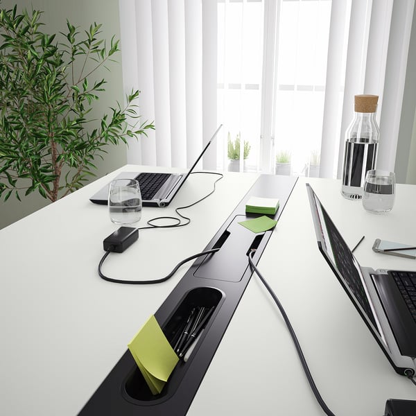 Table de bureau moderne avec gestion des câbles intégrée et repose-pieds, idéale pour les réunions.