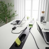 Table de bureau moderne avec gestion des câbles intégrée et repose-pieds, idéale pour les réunions.