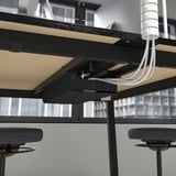 Table de conférence haute avec gestion intégrée des câbles et repose-pieds, idéale pour s’asseoir ou se tenir debout.