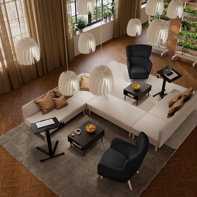 Salon moderne avec parquet, canapé sectionnel, bureaux, fauteuil et lampes. Tapis et plantes près des fenêtres.