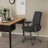 Chaise de bureau MULLFJÄLLET noire dans le bureau à domicile avec ordinateur portable, lampe et tasse à café.