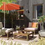 Patio moderne avec meubles NÄMMARÖ gris, parasol orange, coussins, plantes et tapis.