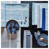 Nappe bleue et blanche avec un motif subtil, fabriquée à partir de coton et de jute, assurant la durabilité. Rehaussé de mûres et de cuillères.
