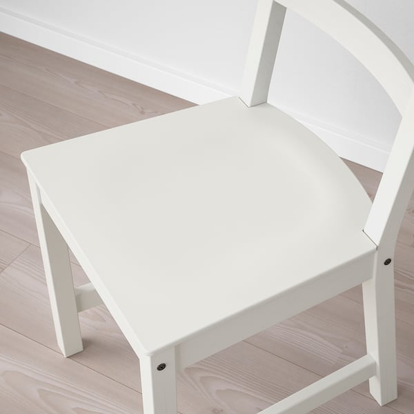 Chaise en bois blanc avec un dossier haut sur un plancher en bois clair. La chaise a une assise profonde et une surface lisse et finie.