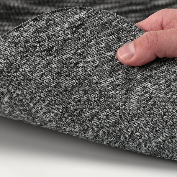 Pose à la main un coussin d’assise gris sur la chaise, mettant en valeur son dessous antidérapant pour un confort stable.