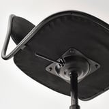 Détail du dessous de la chaise de bureau noire : base en métal robuste, assise en mousse dense, mécanisme lisse.