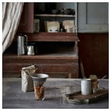 Cuisine vintage avec installation de café, y compris un filtre à café argenté, des grains en sac et des récipients avec des ustensiles sur une table en bois rustique.