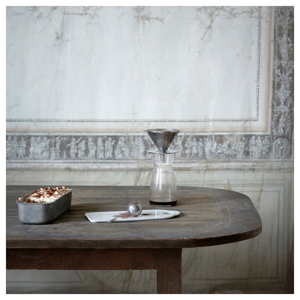 Filtre à café ÖVERST en argent sur table rustique avec serveur en verre et marc de café.