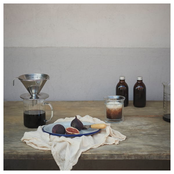 Filtre à café en métal argenté sur la table avec des fruits et des bocaux.