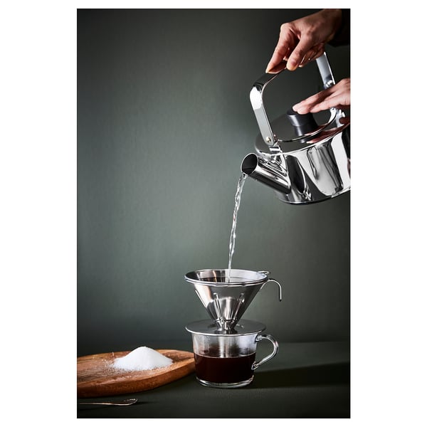 Verser de l’eau dans la cafetière sur une tasse sur une surface verte, du sucre à proximité.