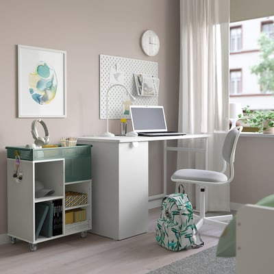 Bureau à domicile avec chariot de rangement, ordinateur portable et chaise. Fournitures, crochet, affiche et sac à dos. Éclairé naturellement.