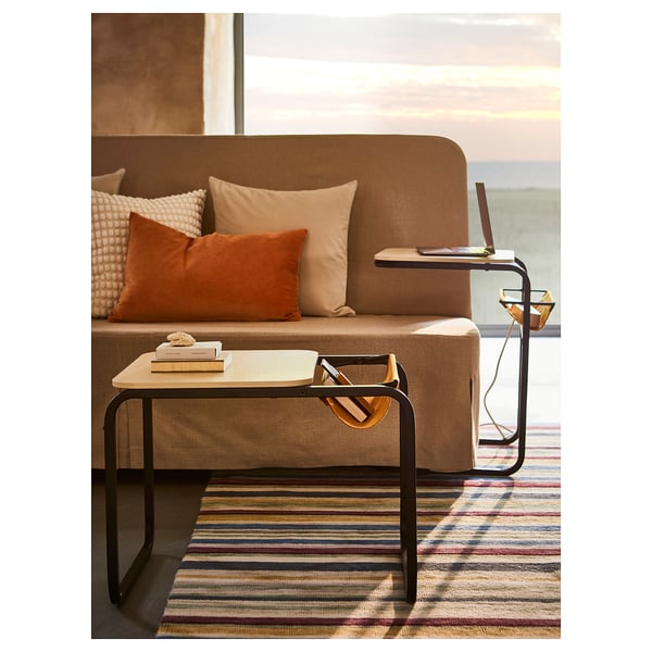 Salon moderne avec table basse OLSERÖD, noir avec plateau en bois clair, plateau de rangement et tapis à rayures.