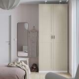 Chambre moderne avec armoire IKEA PAX, miroir et lit rose-beige.