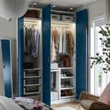 Armoire bleue ouverte montrant des vêtements, des chaussures et des boîtes de rangement, avec éclairage intégré.