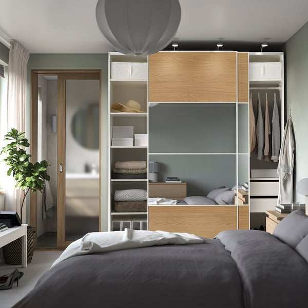 Chambre moderne avec armoire PAX avec portes coulissantes, étagères et éclairage intégré.