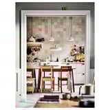 Cuisine confortable avec table en bois rouge, sols chauds et lumières modernes.