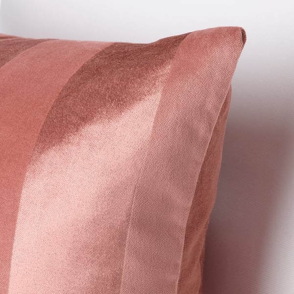 Gros plan d’un oreiller à larges rayures rose pâle, mettant en valeur un bord zippé, mettant en valeur son tissu texturé de qualité supérieure.