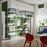 Bureau à domicile moderne avec murs verts, étagères blanches, chaises rouges et parquet. Bien organisé avec des livres, de la décoration et une configuration informatique.