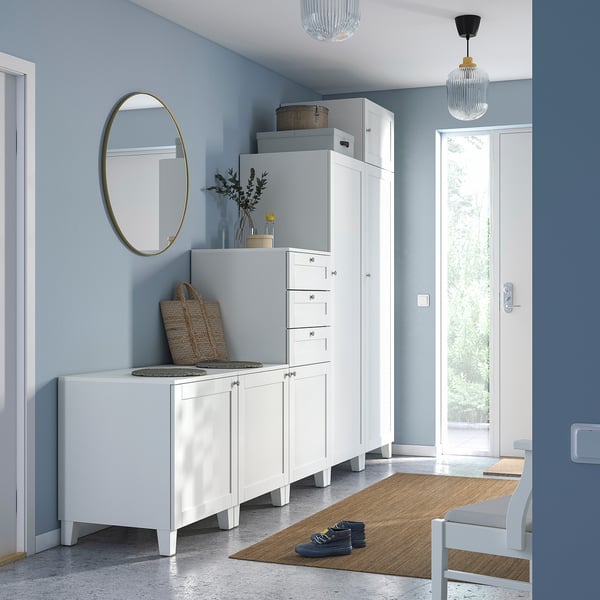Entrée moderne avec meubles de rangement PLATSA blancs, miroir, suspensions, tapis et banc en jute, murs gris.