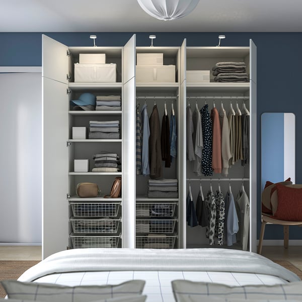 Chambre avec lit blanc, mur bleu, armoire PLATSA montrant les vêtements.