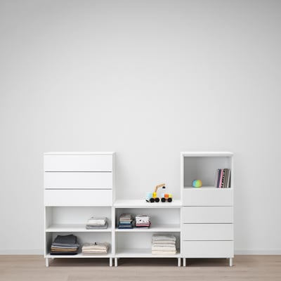 Meubles de rangement modernes blancs avec étagères. Contient des vêtements pliés et des jouets pour enfants. Fixé au mur, stable et modulaire.