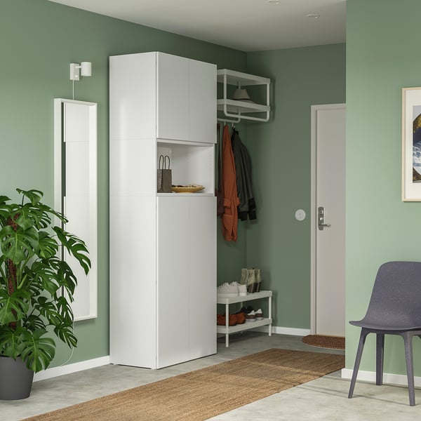 Chambre verte avec des unités PLATSA blanches, des manteaux, une chaise bleue, une plante.