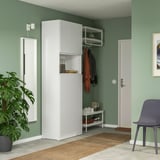 Chambre verte avec des unités PLATSA blanches, des manteaux, une chaise bleue, une plante.