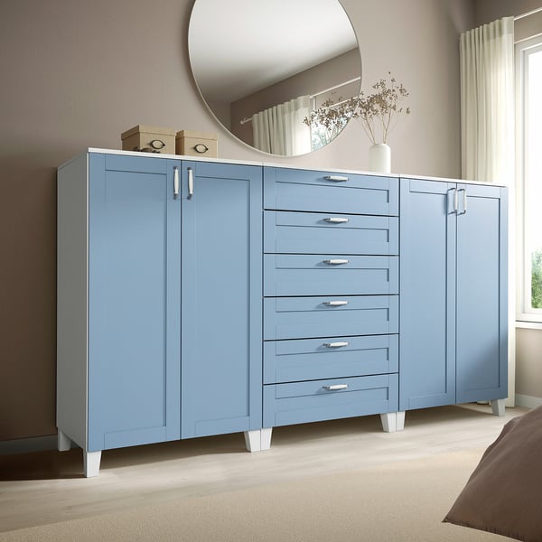 Unité de rangement PLATSA bleue dans la chambre. Grande commode à six tiroirs avec armoires, plancher en bois clair, murs beiges.