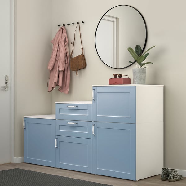 Entrée moderne avec des unités de rangement PLATSA bleu clair avec dessus blanc, miroir rond, manteau suspendu et petite plante.
