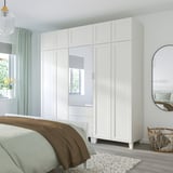 Chambre moderne avec grande armoire PLATSA, portes miroir, literie neutre, panier tressé, miroir rond, parquet clair.