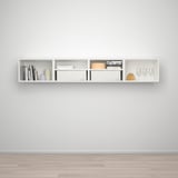 Étagère murale blanche avec compartiments pour ranger livres, vases, boîtes et verres à vin.