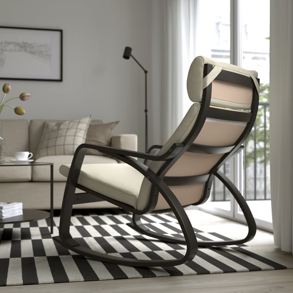 Fauteuil à bascule en métal noir avec coussins beiges sur tapis à carreaux noir et blanc dans un salon moderne.