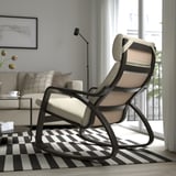 Fauteuil à bascule en métal noir avec coussins beiges sur tapis à carreaux noir et blanc dans un salon moderne.