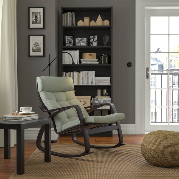 Salon moderne avec fauteuil à bascule POÄNG, étagère, table et fenêtre.