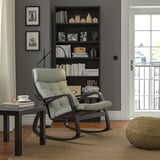 Salon moderne avec fauteuil à bascule POÄNG, étagère, table et fenêtre.