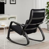 Fauteuil à bascule noir avec dossier haut et accoudoirs incurvés, idéal pour se détendre. Positionné sur un tapis de couleur claire dans un espace de vie confortable.