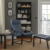 Salon confortable avec fauteuil et repose-pieds bleu foncé, coussins moelleux, étagère, tapis, éclairage chaleureux.