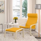 Fauteuil POÄNG jaune moutarde avec pouf, coussins épais, cadre en bois clair, fenêtre à rideaux blancs.