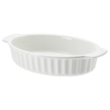 Un plat de cuisson ovale en céramique blanche avec des poignées et une texture côtelée.