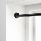 Support de tringle à rideau noir monté sur un mur blanc, conçu pour une suspension sûre et réglable des rideaux.