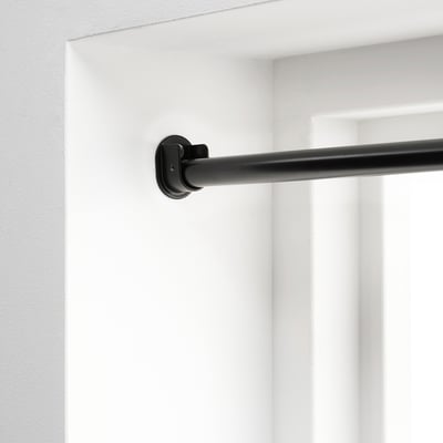 Support de tringle à rideau noir monté sur un mur blanc, conçu pour une suspension sûre et réglable des rideaux.