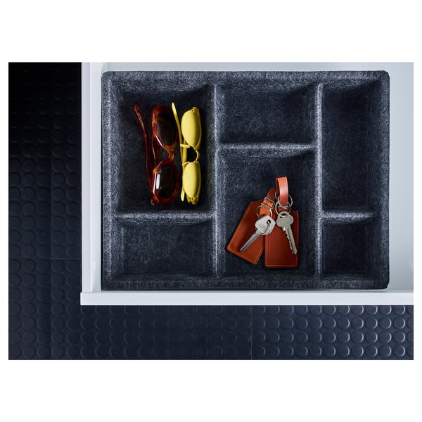 Plateau de rangement noir avec compartiments, contenant des lunettes de soleil rouges et jaunes, et un porte-clés avec des clés. Fabriqué en polyester.