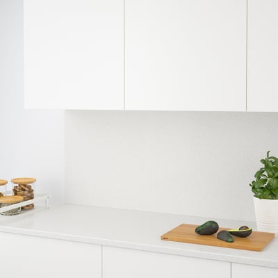 Comptoir de cuisine moderne avec un dosseret en quartz, exposant des avocats sur une planche à découper.