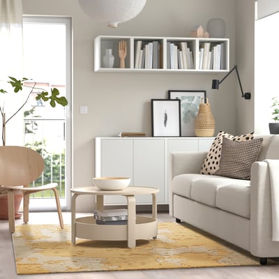 Salon moderne avec canapé gris, chaise en bois, table basse et tapis RINGKLOCKA. Buffet blanc, lampe, œuvre d’art et grande fenêtre pour la lumière naturelle.