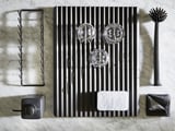 Accessoires de cuisine noirs, y compris séchoir, brosse, porte-éponge et épurateur sur une surface en marbre.